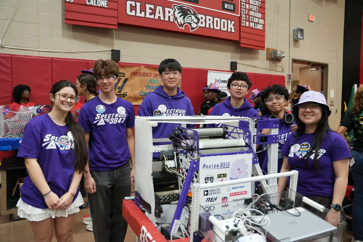 Photon 8515 students standing with their robot in the pit at a district competition
